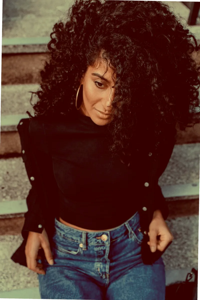 Aliyah Moore - a woman with curly black hair wearing a black top and jeans